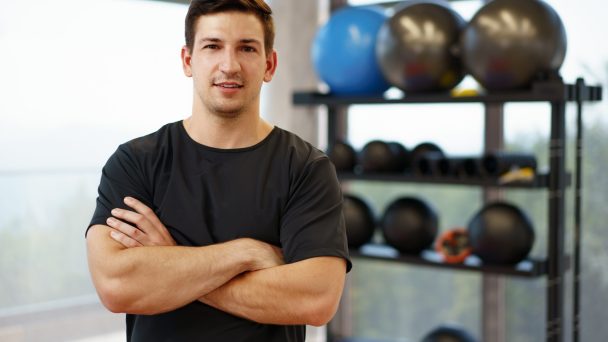 Portrait of a young handsome fitness trainer in a gym, close up